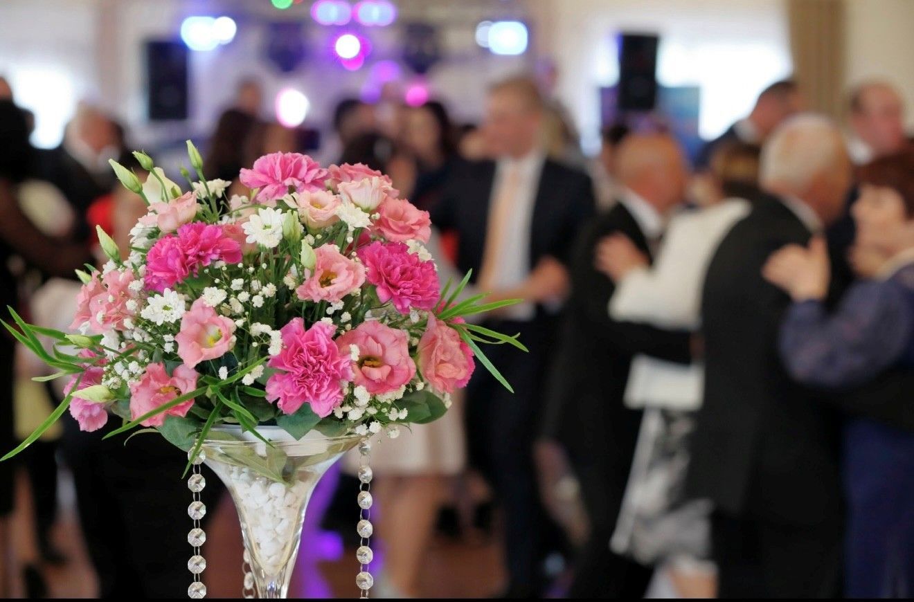 Elegant event hall with round tables, floral centerpieces, and dancers.
