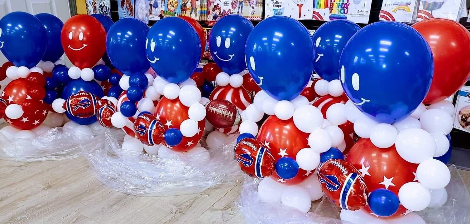 Red, white, and blue balloon decorations arranged in clusters on a table, with large blue balloons above.