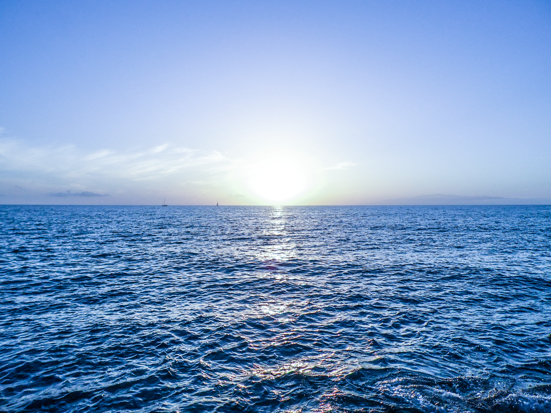 Sunlit ocean horizon with shimmering blue waves under a clear sky