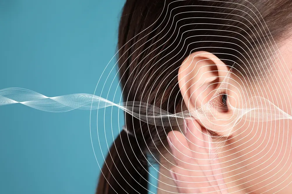 A woman experiencing ringing in her ears due to tinnitus.