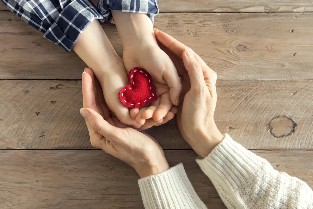 A child giving a heart-shaped item to a parent or guardian.