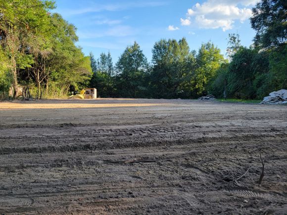 A large dirt field with trees in the background.