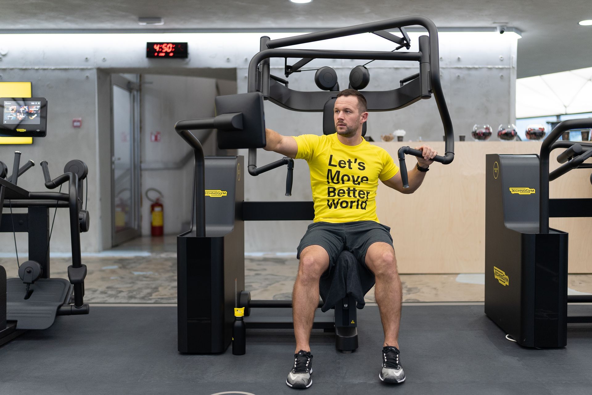 a man in a yellow shirt is sitting on a machine in a gym .