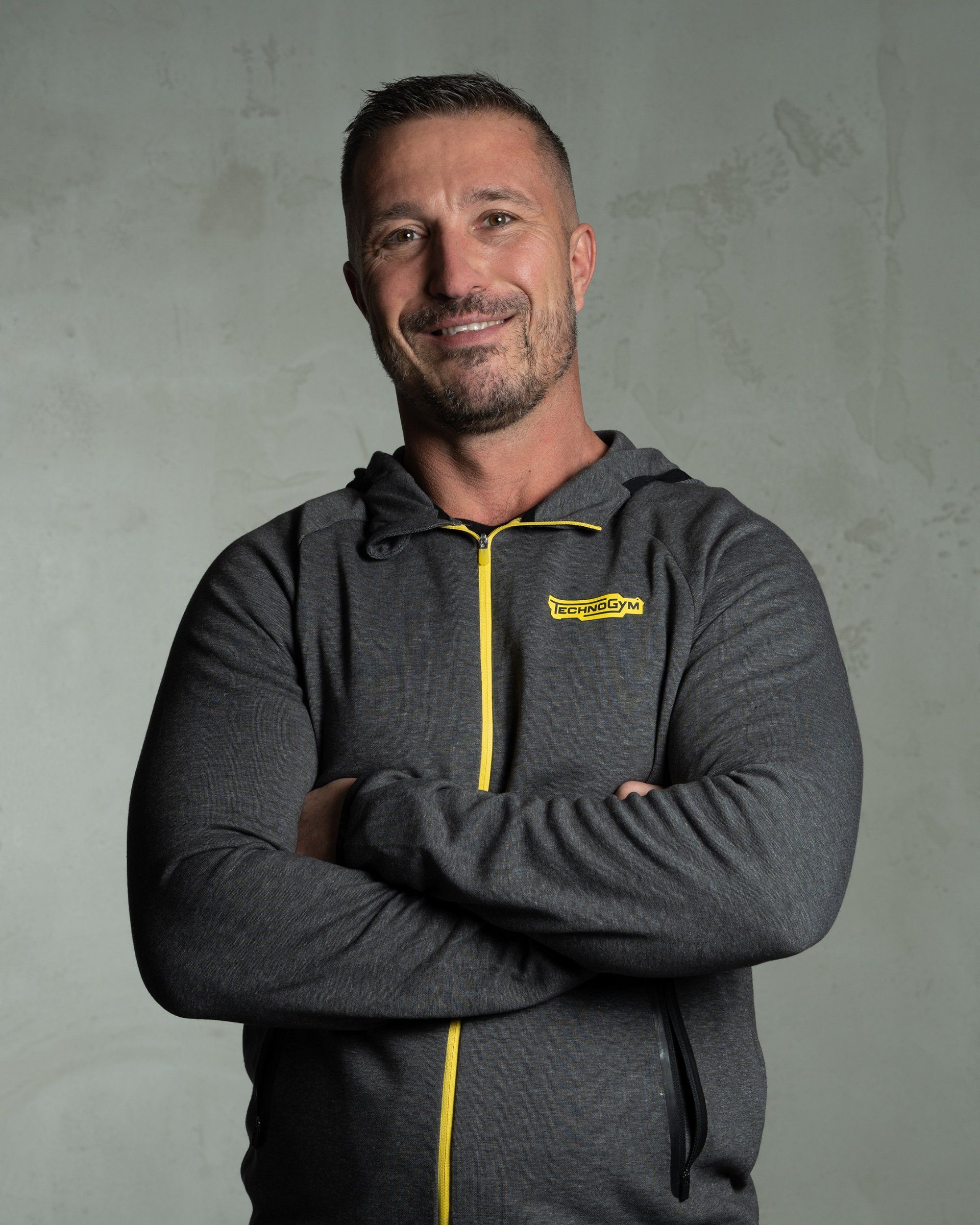 a man wearing a grey hoodie with a yellow zipper