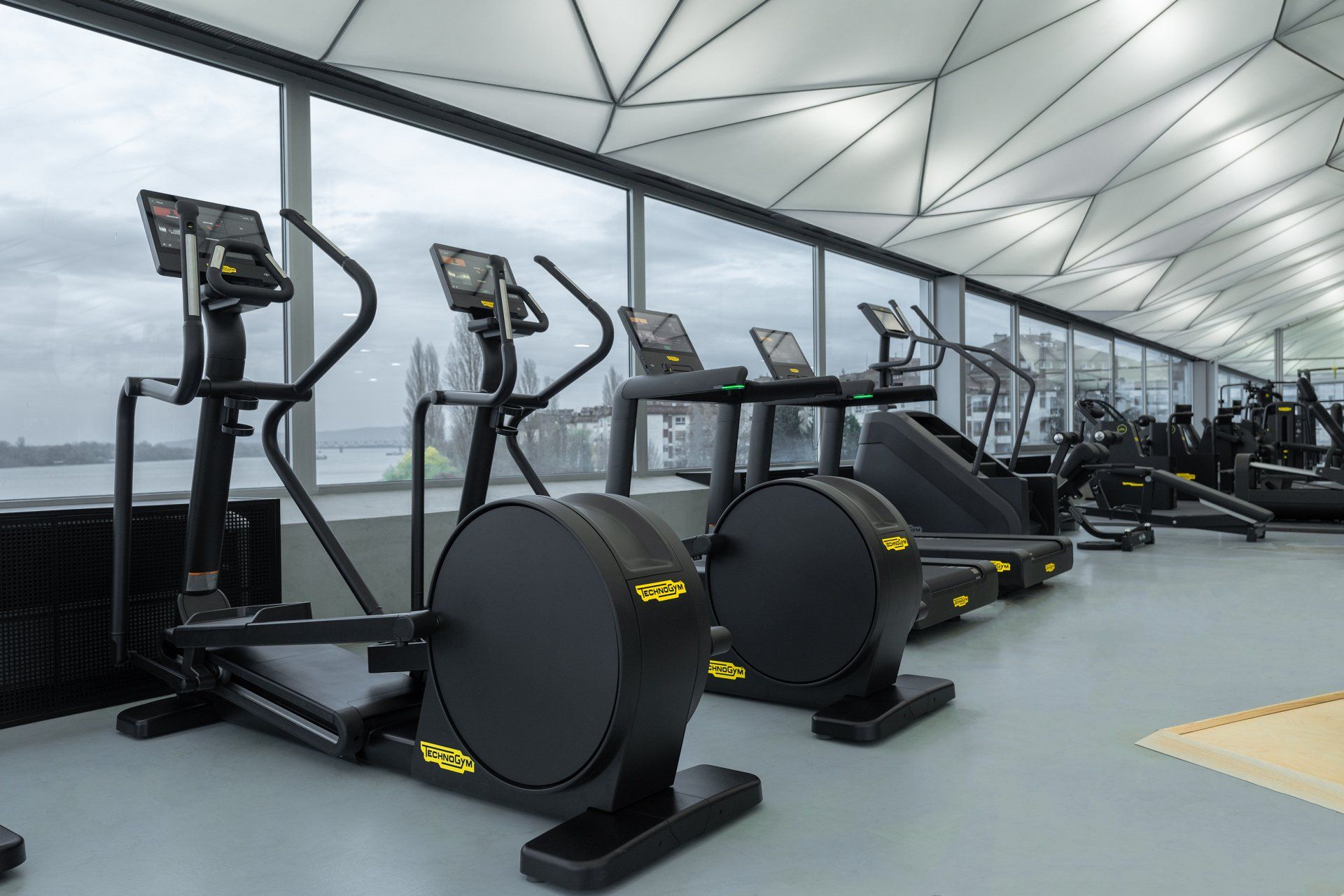 a gym with a lot of exercise equipment and a lot of windows .