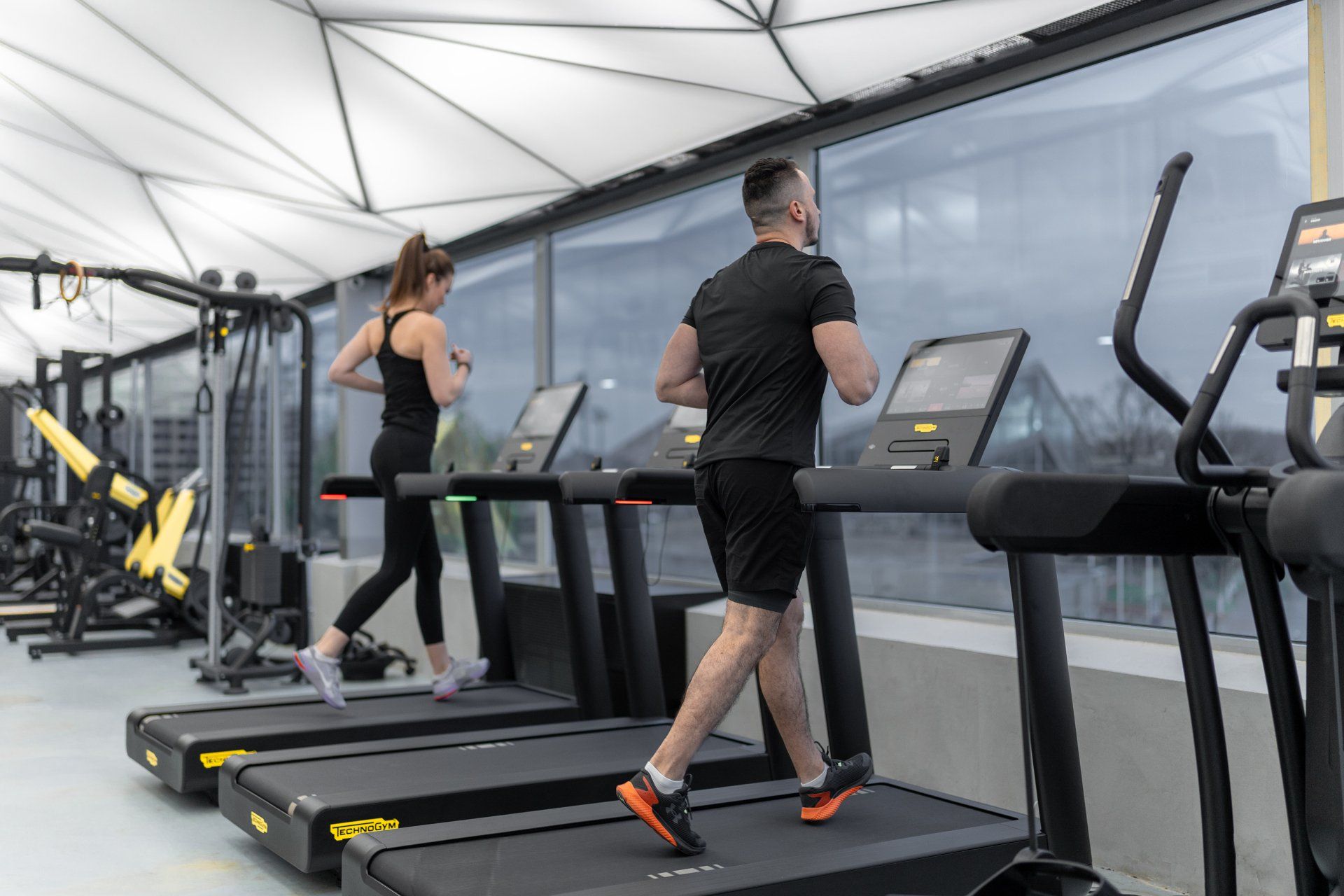a man and a woman are running on treadmills in a gym .