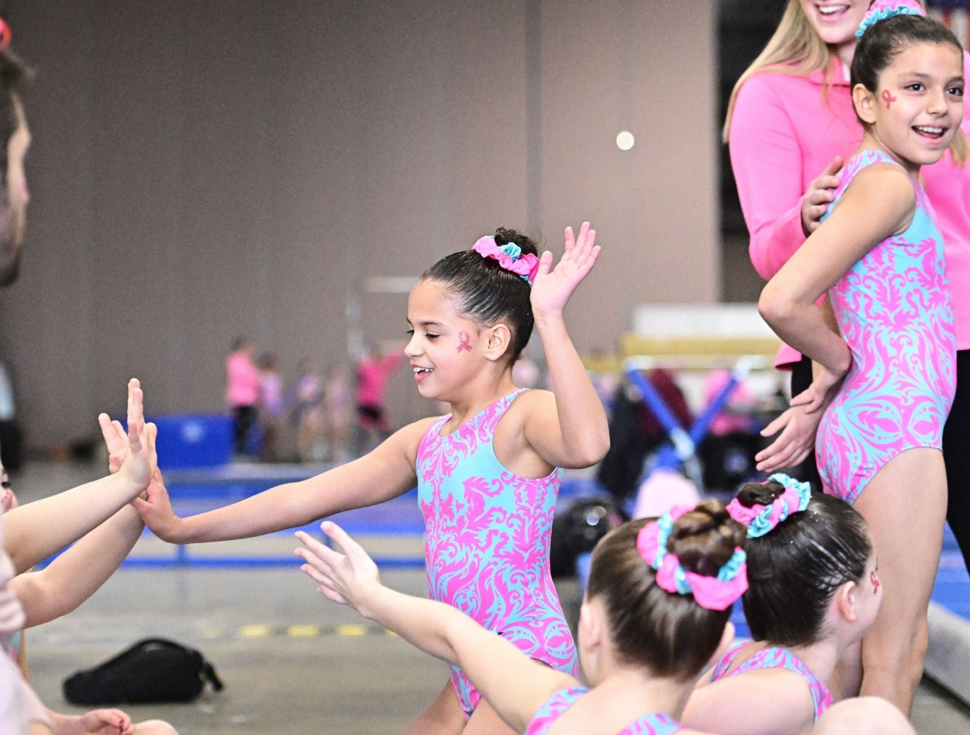 Cheer team in matching blue and black uniforms celebrating in an indoor gymnasium.