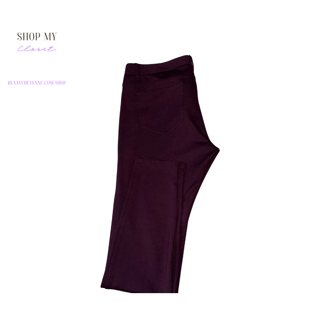 A close-up of a pair of New York and Company Soho cotton burgundy dress pants. The pants are made of a smooth, comfortable fabric and have a straight leg. They are size 12 and are on a hanger. The pants are a deep burgundy color and have a small, white New York and Company logo on the front pocket.