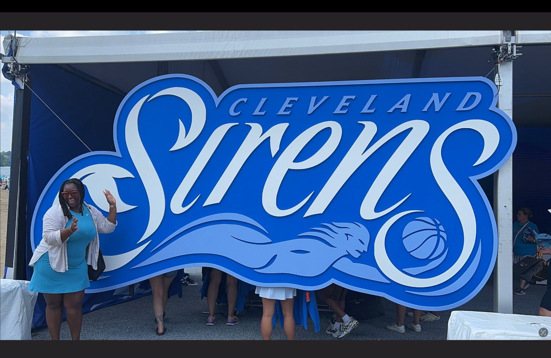 Renay Cheyenne standing beside a large Cleveland Sirens logo near the Center Court pop-up at FanFest.