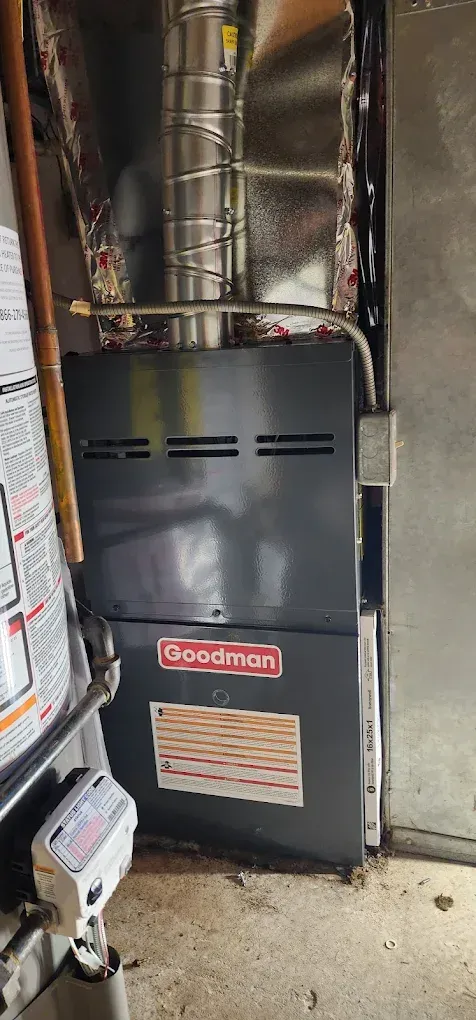 A Goodman furnace installed in a utility room. Chimney and gas line visible.