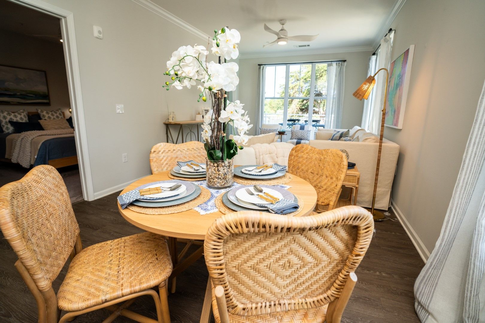 Dining area with round table, woven chairs, and flower centerpiece at The Osprey at Lake Norman, offering luxury apartments in Mooresville, NC.
