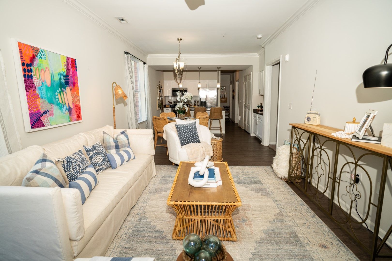 Living room with white sofa, blue and white pillows, art, and a rattan coffee table at The Osprey at Lake Norman, offering Mooresville apartments for rent.