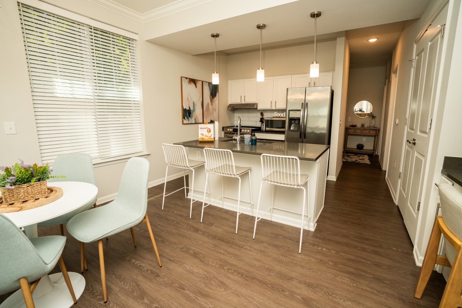 Modern kitchen with island, white cabinets, stainless steel appliances, and a small dining table at The Osprey at Lake Norman, offering Mooresville apartments.