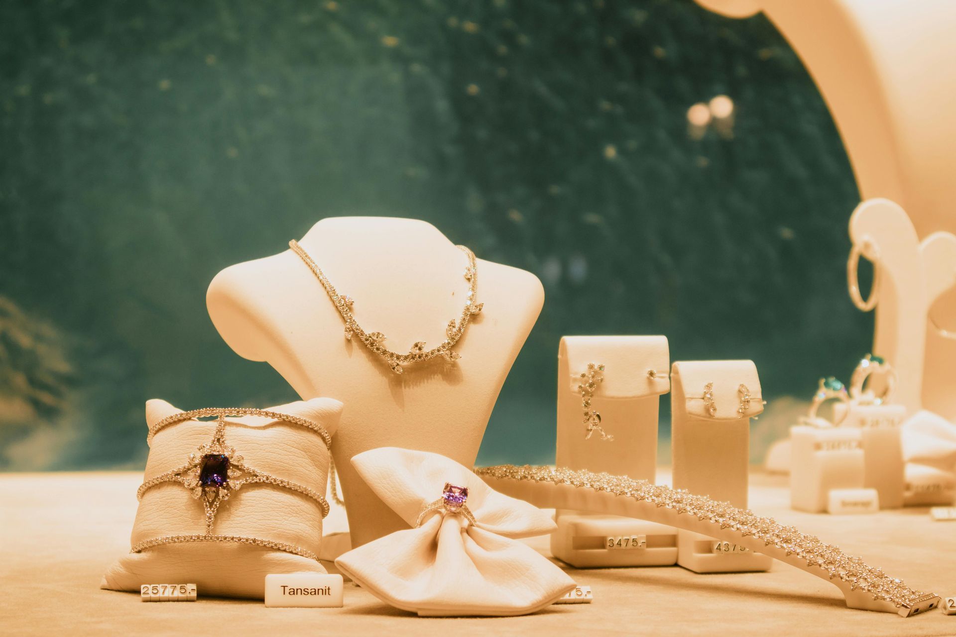 Jewelry display with gold necklaces, bracelets, rings, and a delicate pouch on a beige tabletop