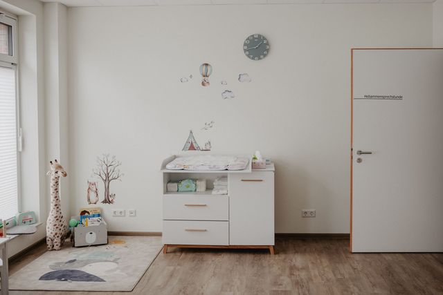 Ein Zimmer mit einem Wickeltisch und einer Uhr an der Wand.