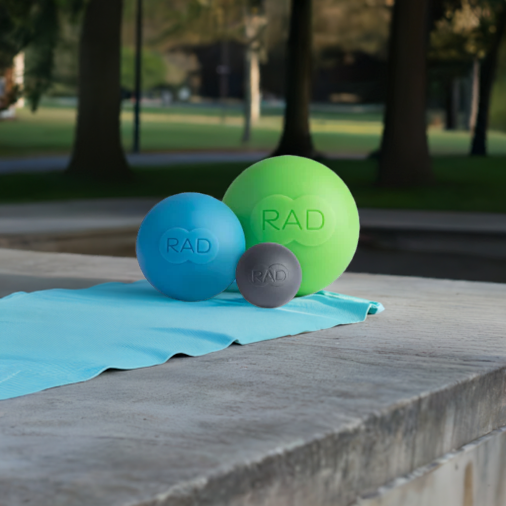 Three rad rounds massage balls are sitting on a blue towel on a concrete surface.