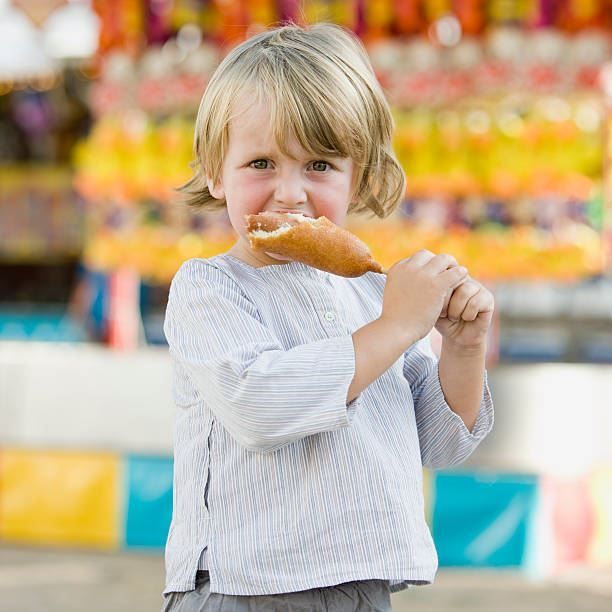 Child holding a pastry in front of a colorful blurred market display