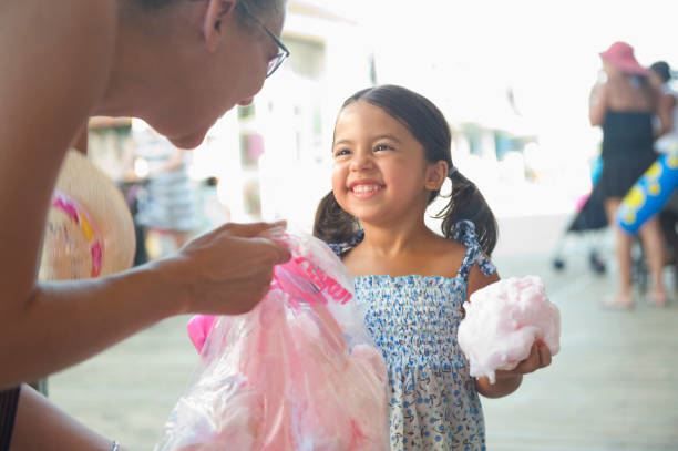 Woman offers cotton candy to smiling child at a fair