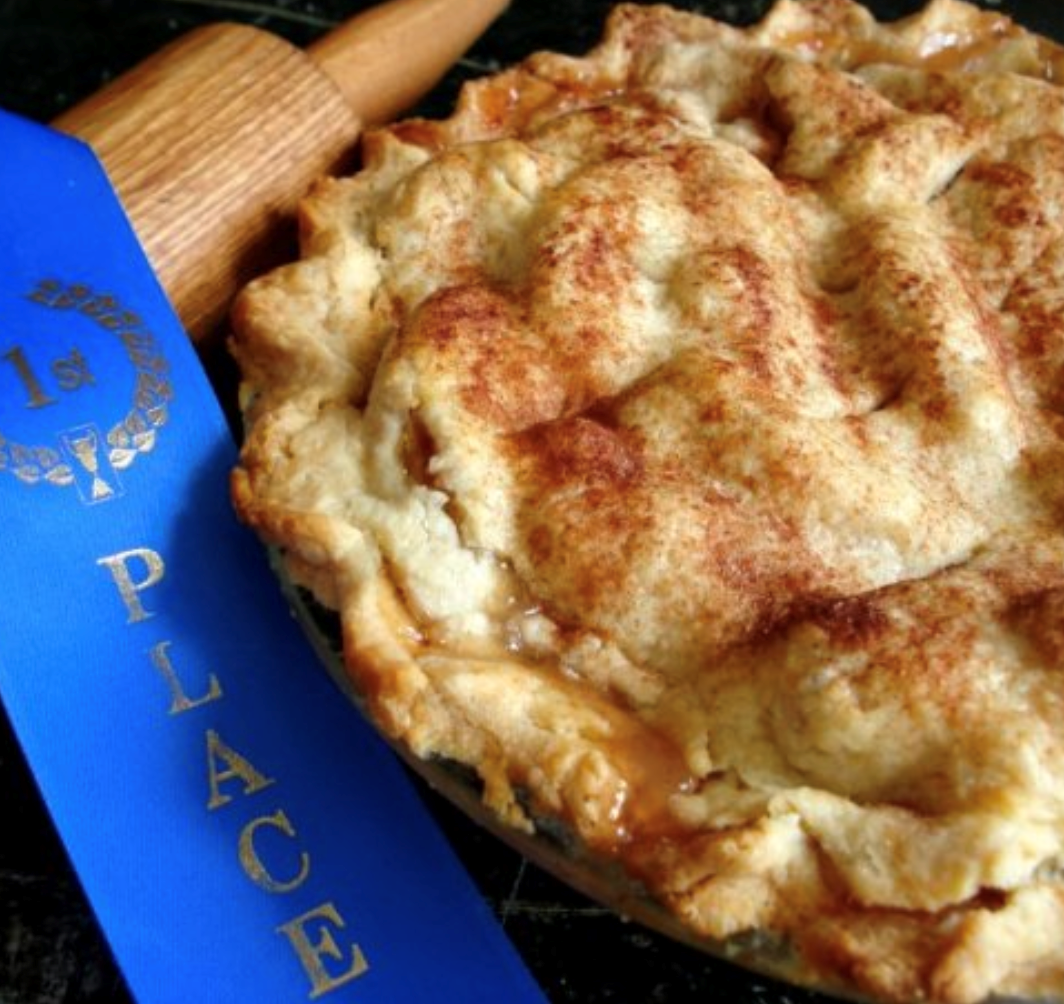 Blue rolling pin beside a golden-brown pie with a crimped crust