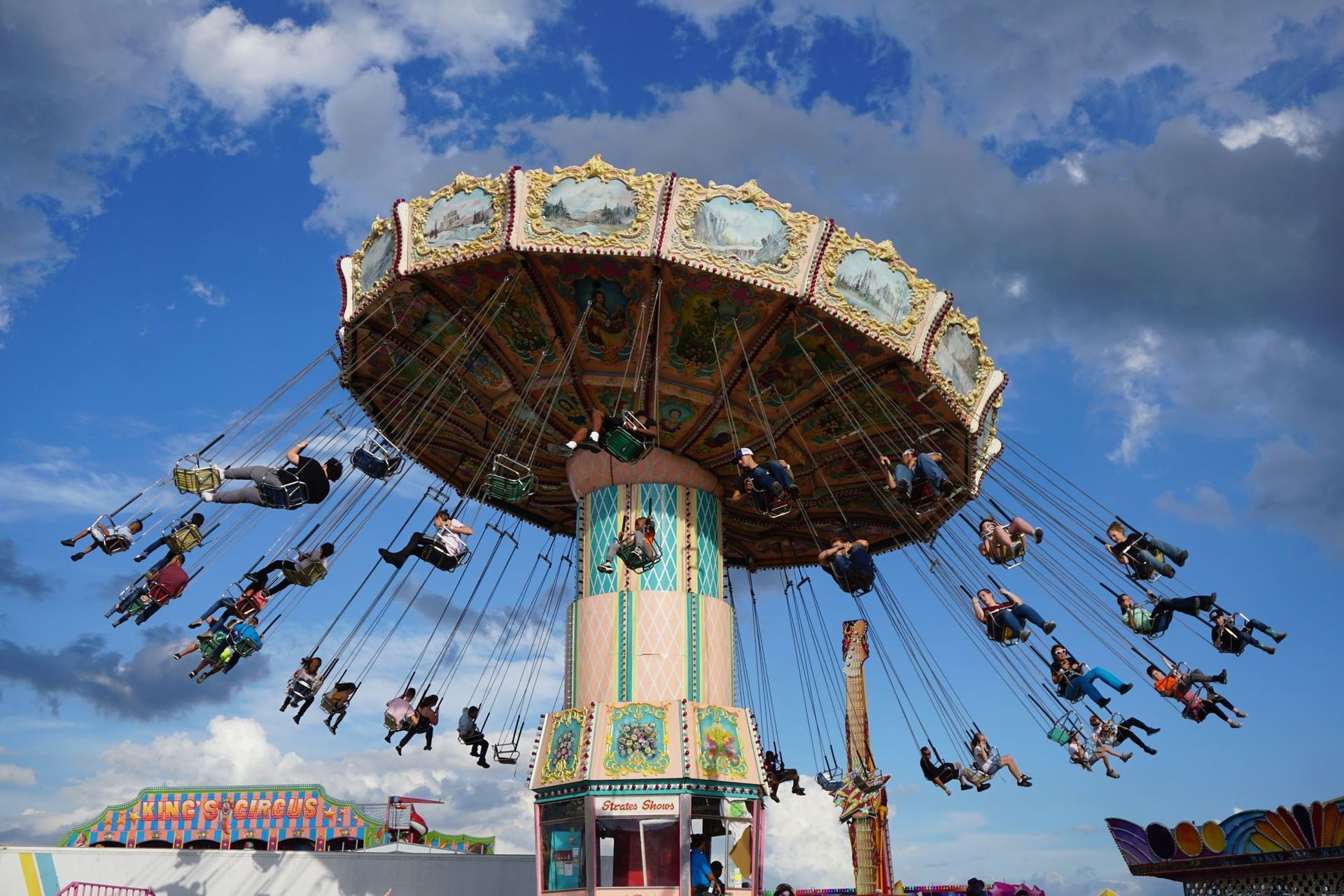 Swing ride with colorful suspended seats spinning against a blue sky with clouds