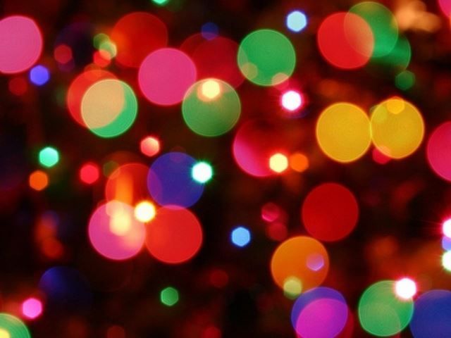 Colorful blurred bokeh lights in red, green, yellow, blue, and pink on a dark background