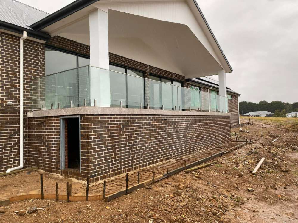 A Brick House With a Glass Railing is Being Built — All Things Windows & Doors in Goulburn, NSW
