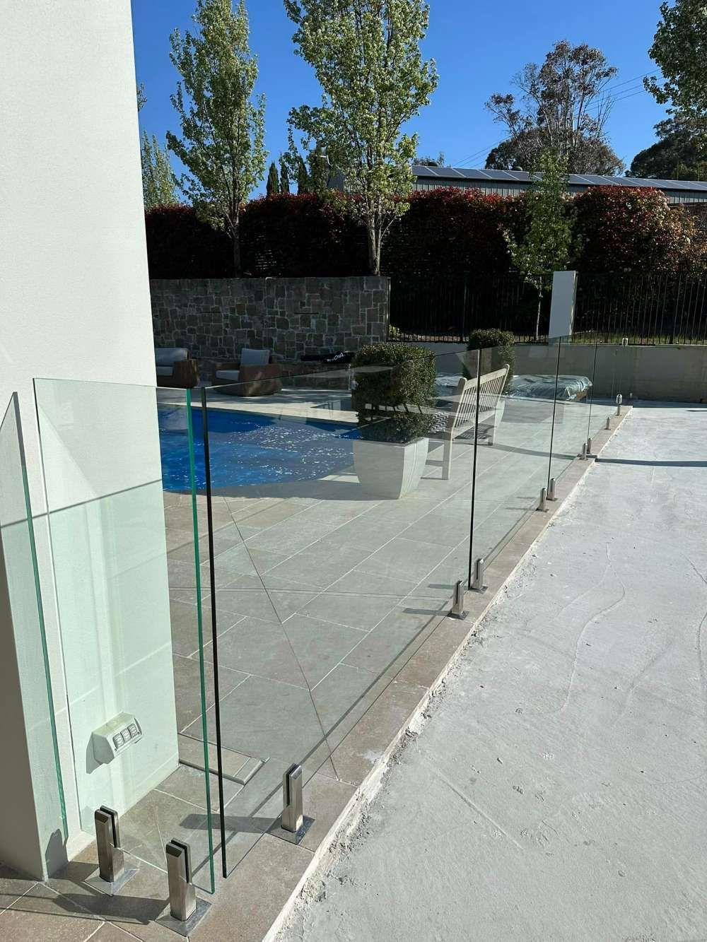 A Glass Fence Surrounds a Swimming Pool — Bespoke Doors & Windows in Goulburn, NSW