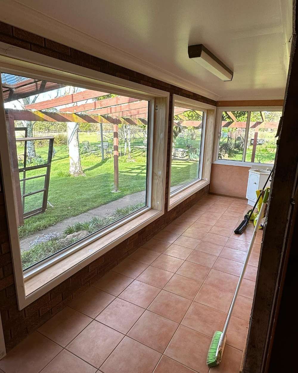 An Empty Room With Large Windows and a Broom on the Floor — Bespoke Doors & Windows in Goulburn, NSW
