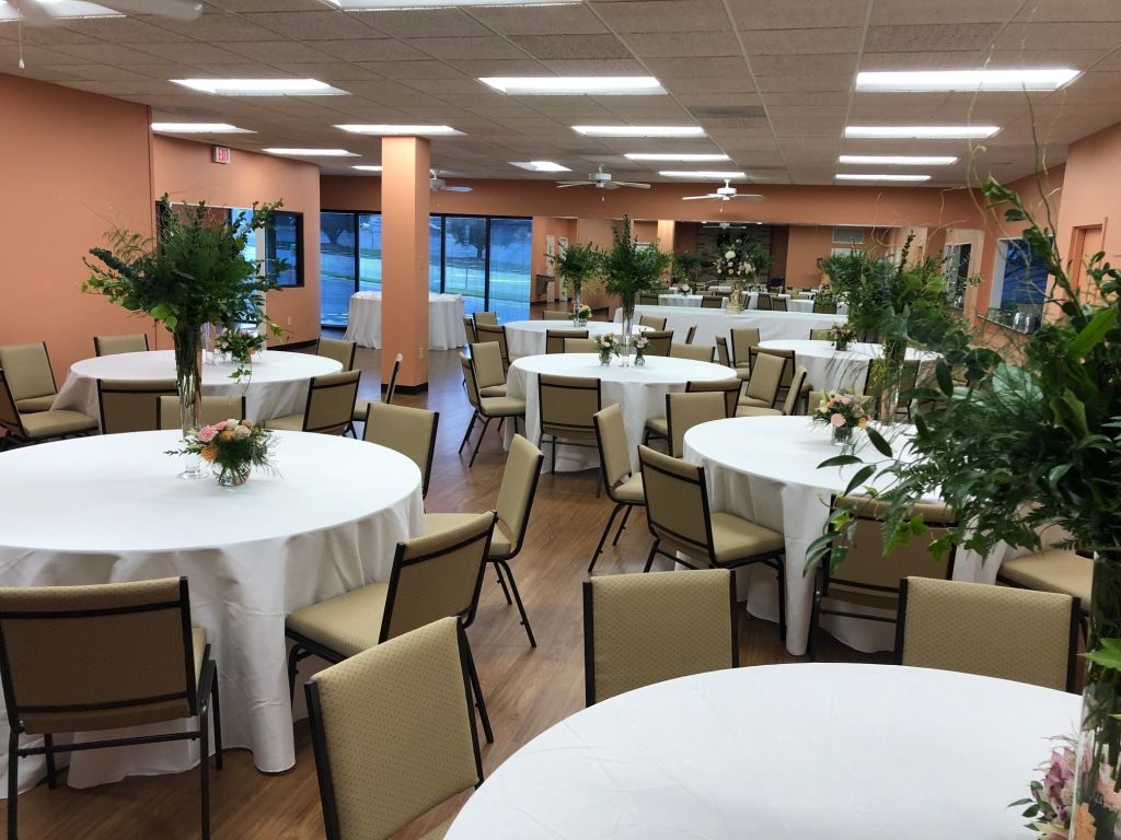A large room with tables and chairs set up for a wedding reception.