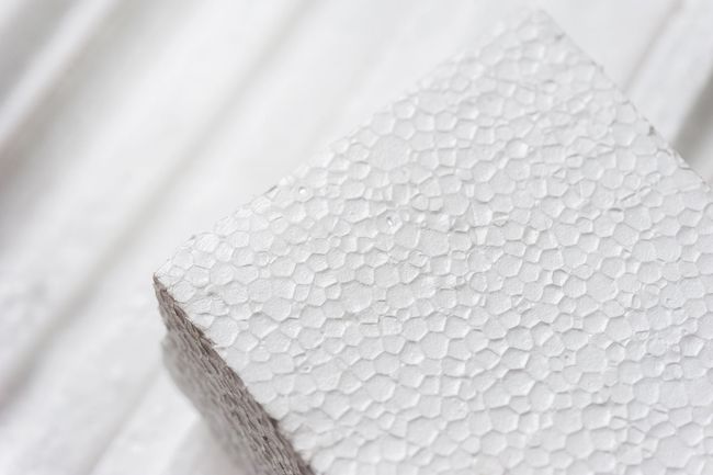 Primer plano de un bloque de espuma blanca con superficie texturizada, sobre un fondo similar.