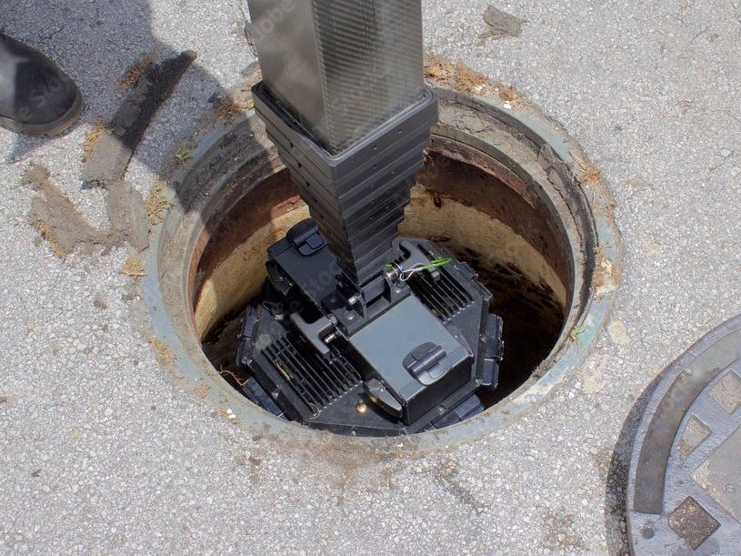 A sewer cover with a camera coming out of it.