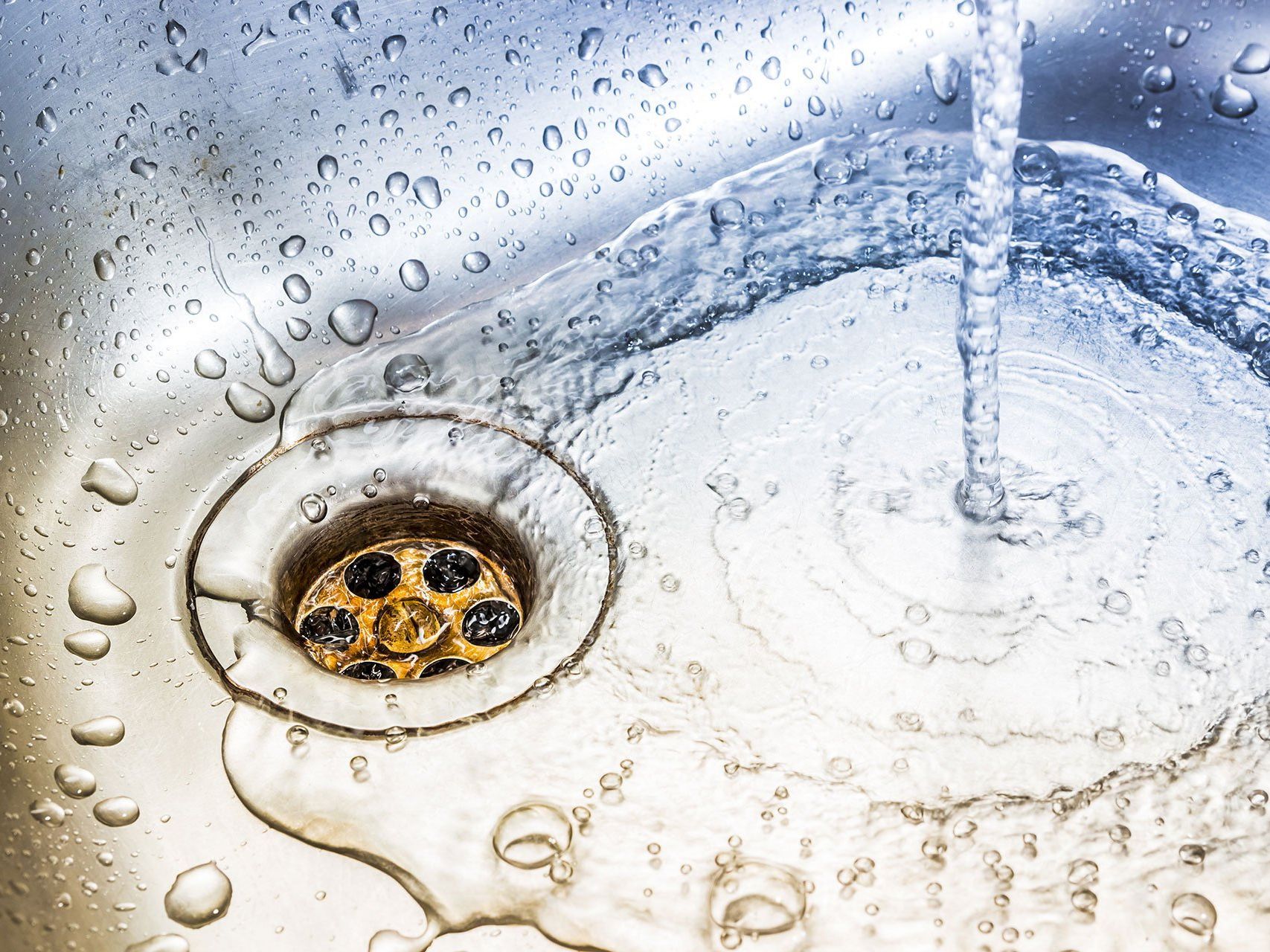 A close up of a sink with water running down the drain.