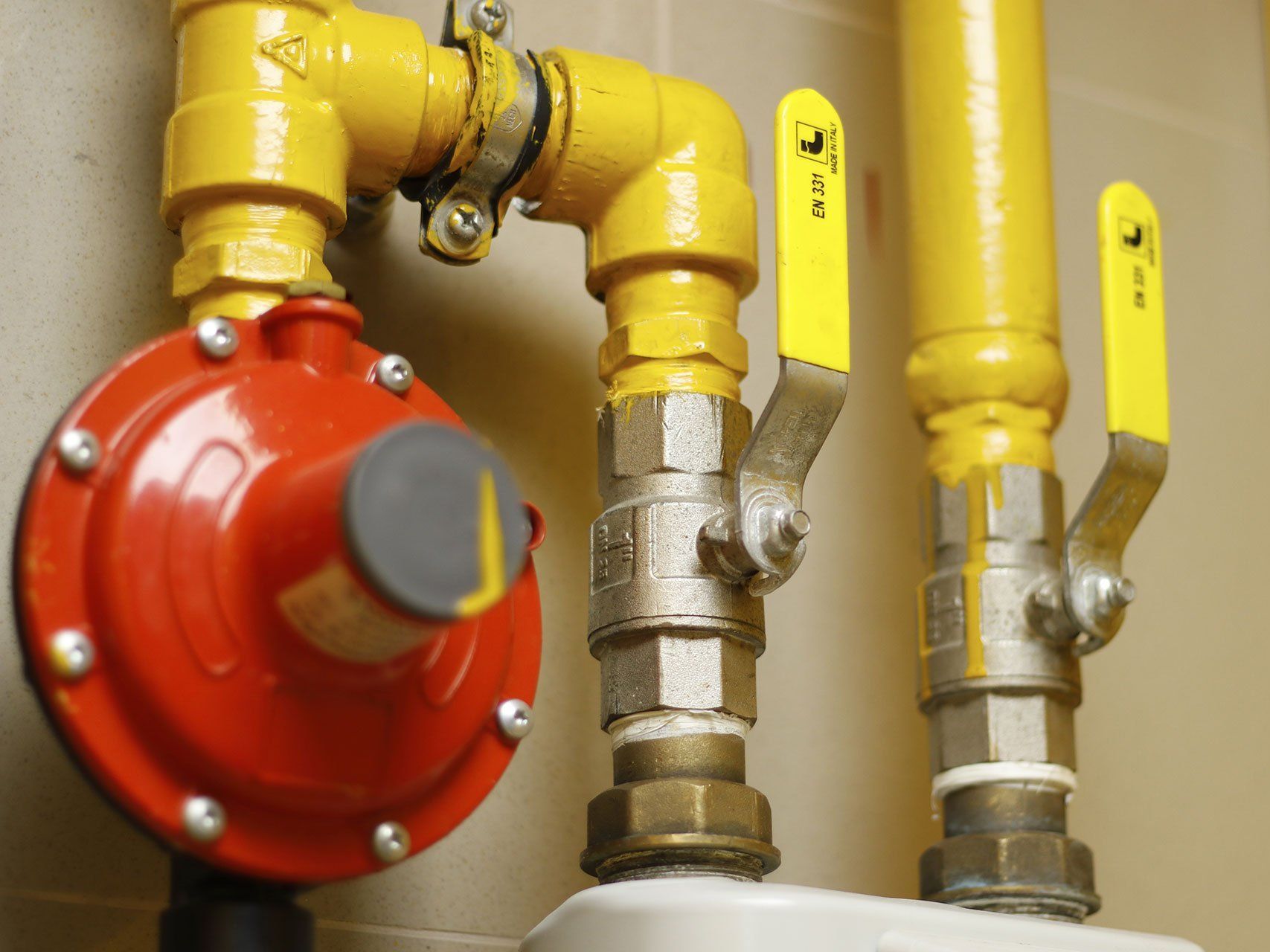 A close up of a gas pipe with yellow valves