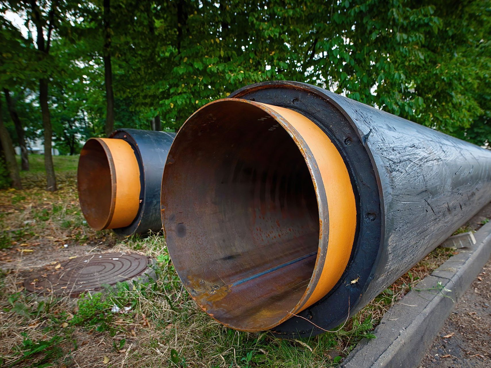 Two large pipes are sitting next to each other in the grass.