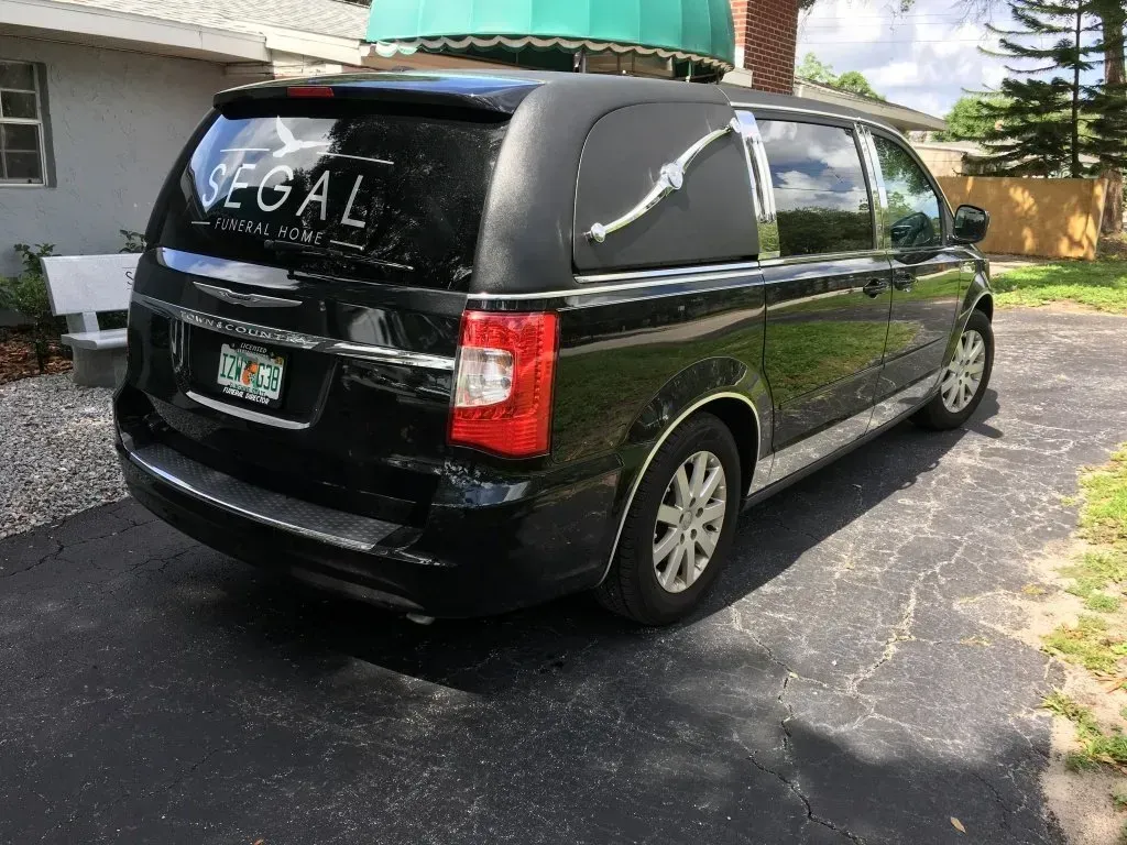 Black SUV parked in a driveway beside a house, with “LEGAL” written on the rear window.
