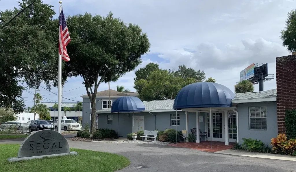 Small building with blue awnings, a U.S. flag, and a sign reading “LEGAL” at the entrance.