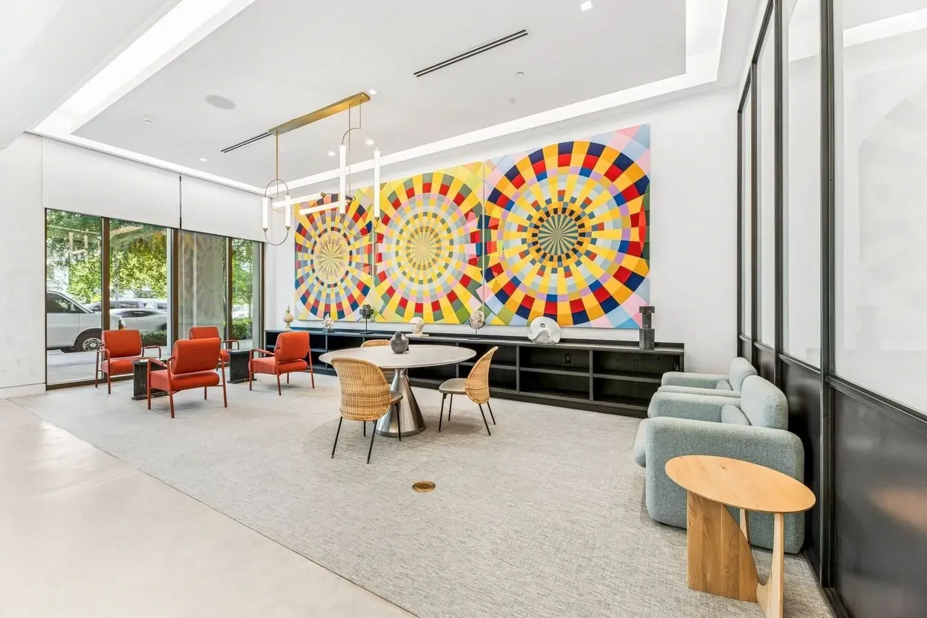 Modern lobby lounge with colorful wall art, orange chairs, and light wood tables