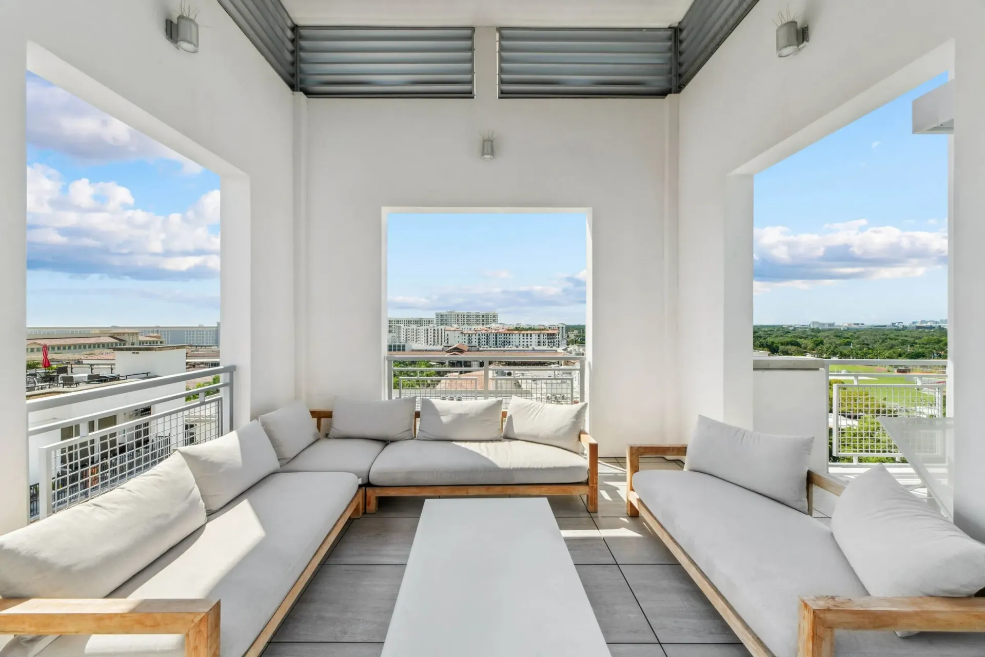 Outdoor balcony lounge area with sectional sofa, coffee table, and city views.
