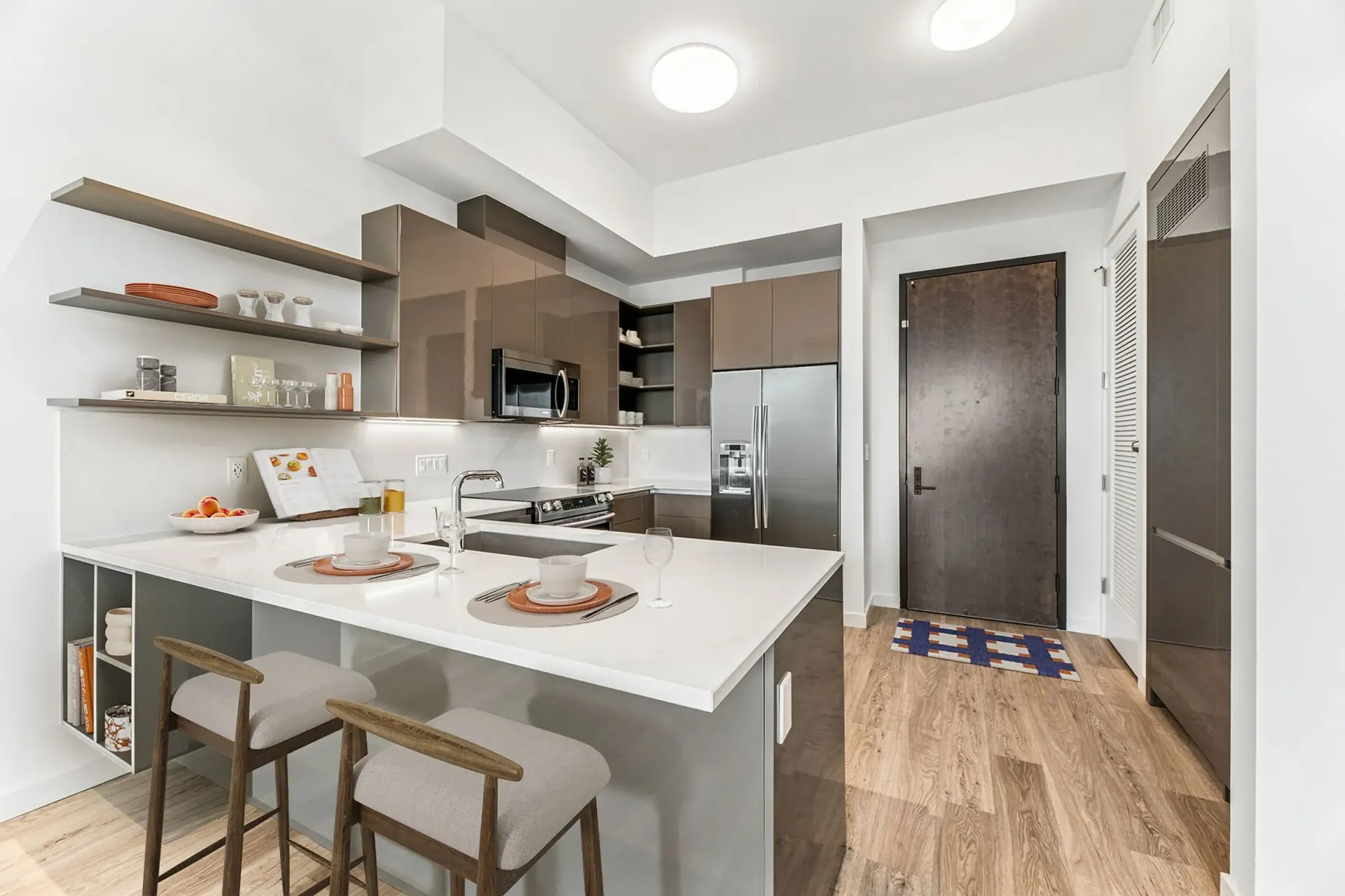 Modern kitchen with stainless steel appliances, island with seating, and wood-look flooring.