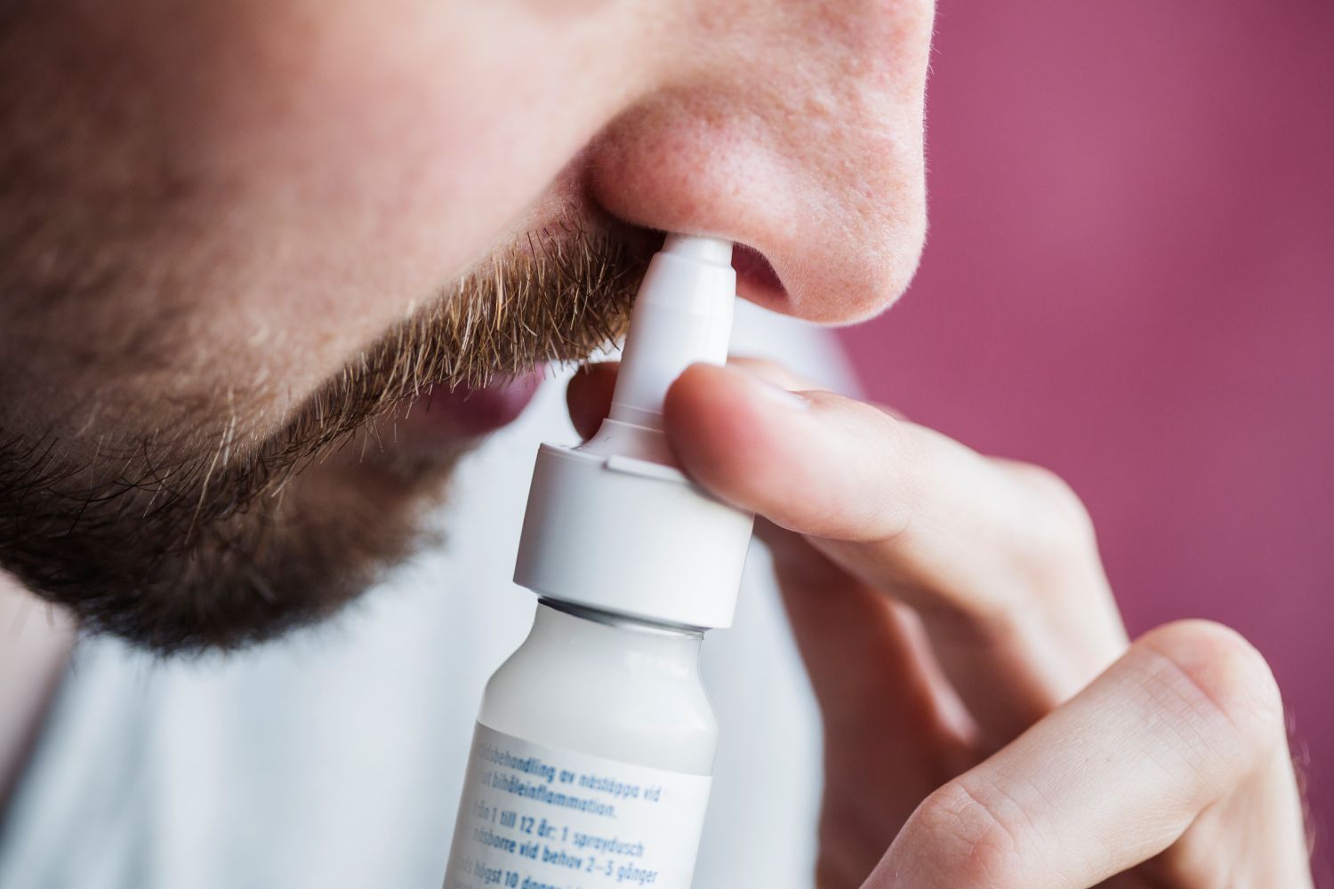 Close up of a man using a nasal spray