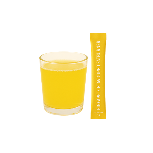 Een glas gele vloeistof naast een zakje vetverbrander met ananassmaak.