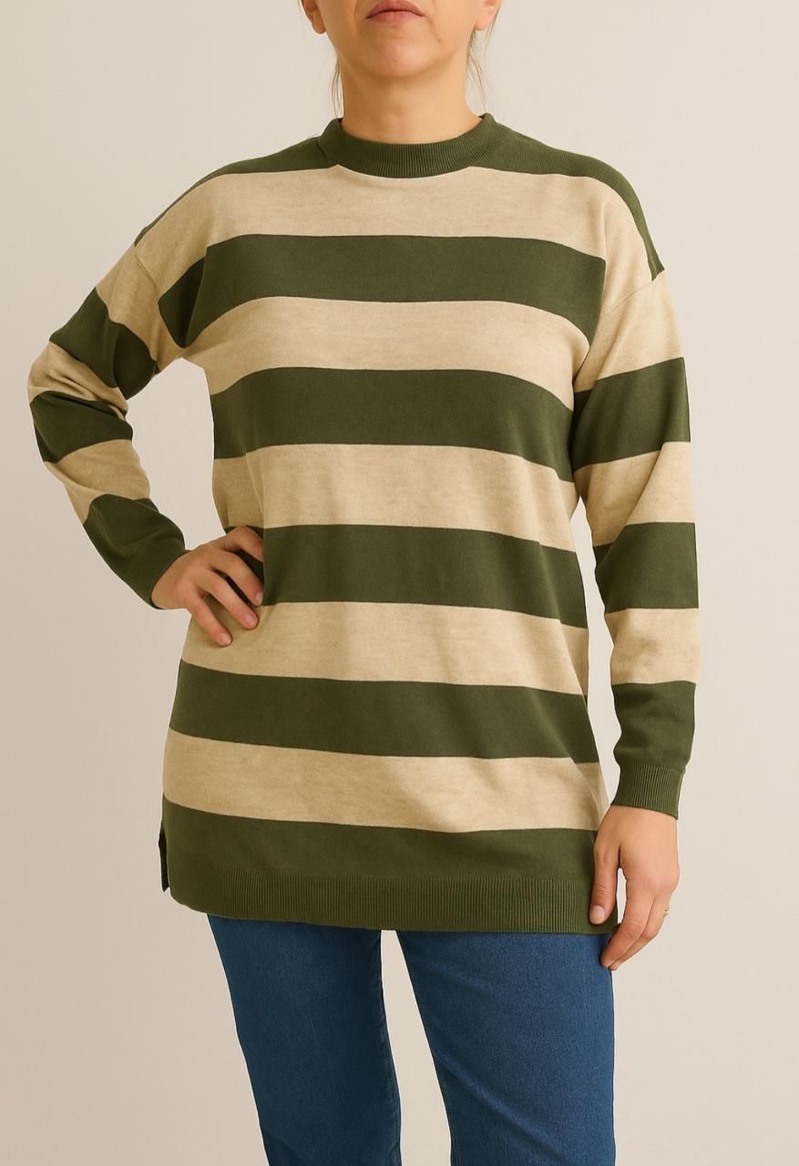 Mujer con un suéter de rayas verdes y beige, con las manos en la cadera y vistiendo jeans azules.