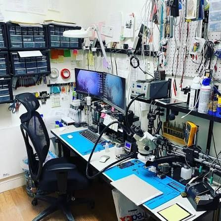 Technician workbench with an open phone, screwdrivers and a tablet mid-repair