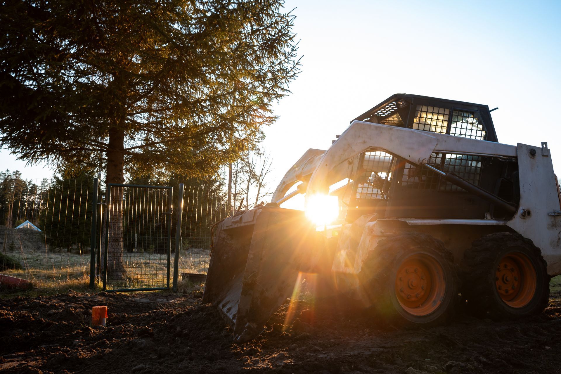 Skid steer loader at sunset on a dirt.