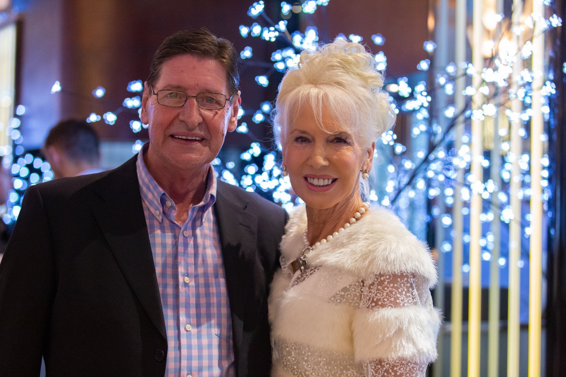 A man and a woman are posing for a picture in front of a christmas tree.