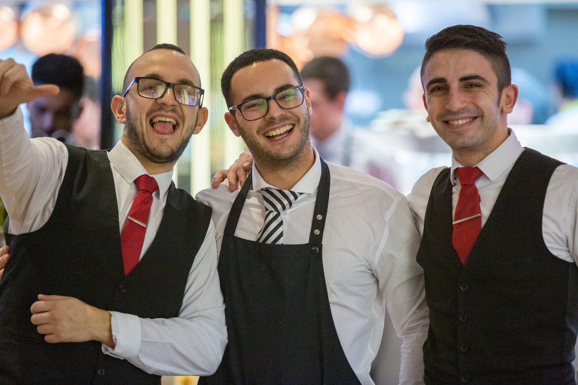Three men wearing aprons and ties are posing for a picture.