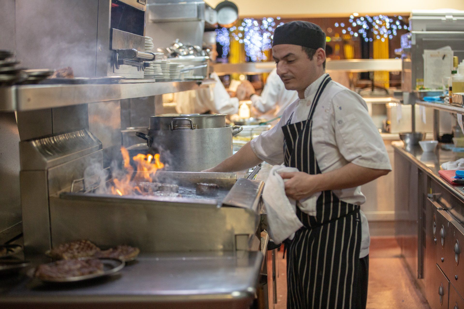 A chef is cooking food on a grill in a kitchen.