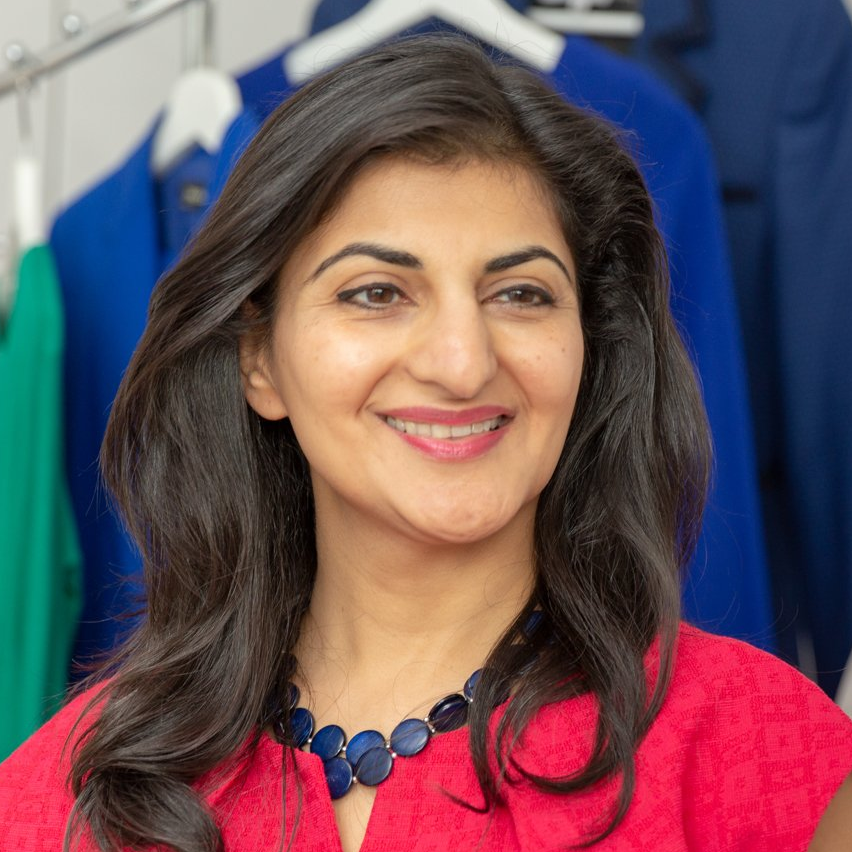 A woman wearing a red shirt and a blue necklace is smiling.