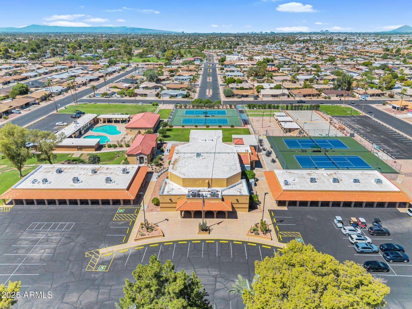 Aerial view of a school campus with buildings, playgrounds, parking lots, and a road stretching into the distance.
