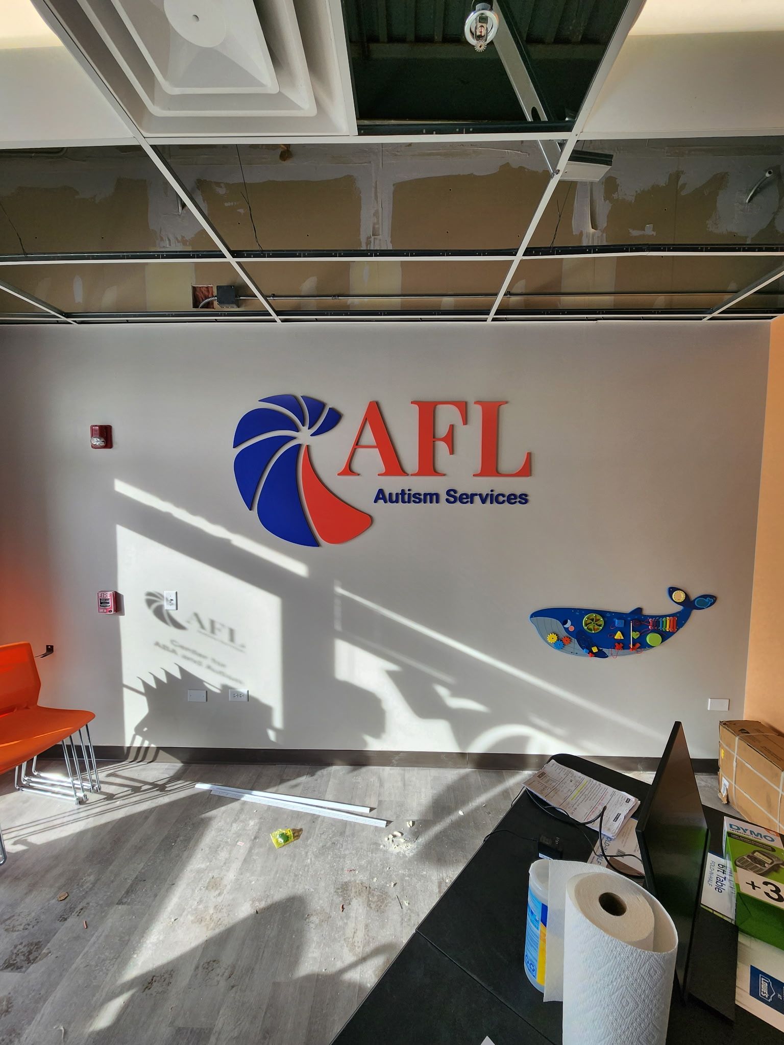 AFL Federal Services wall logo in a bright office lobby with scattered debris and ceiling exposed above